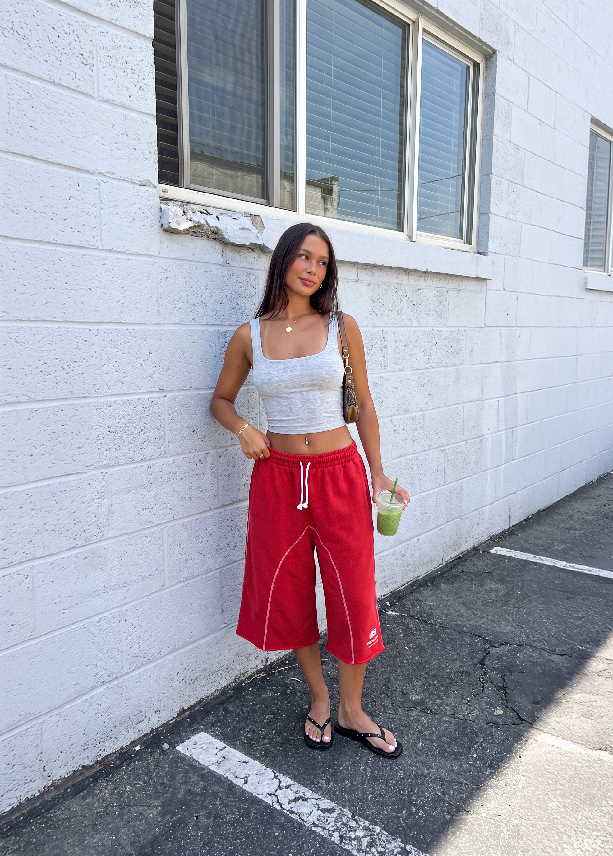 Model in a white tank and red trousers against a white wall