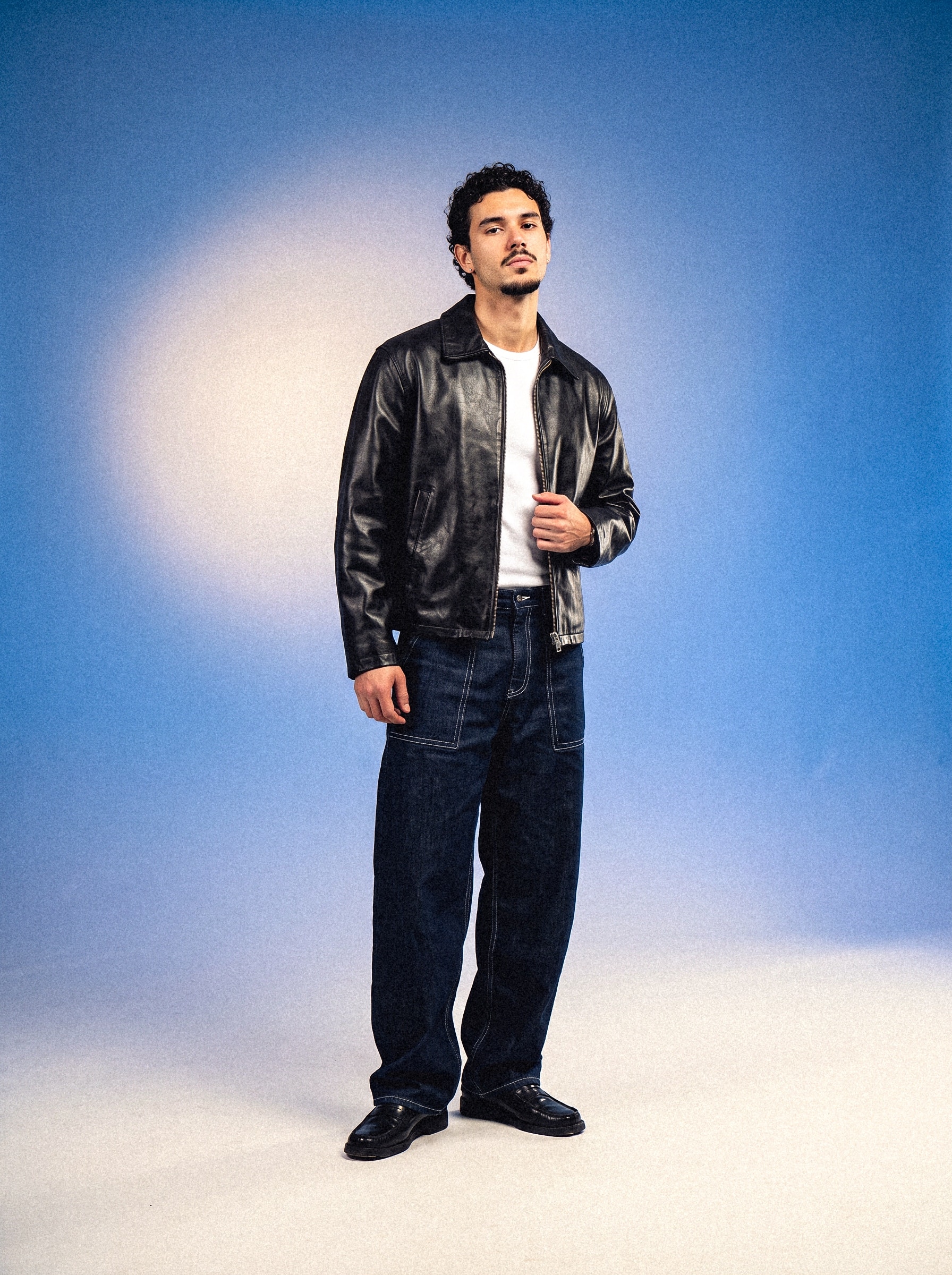 Model in a leather jacket on a blue studio backdrop