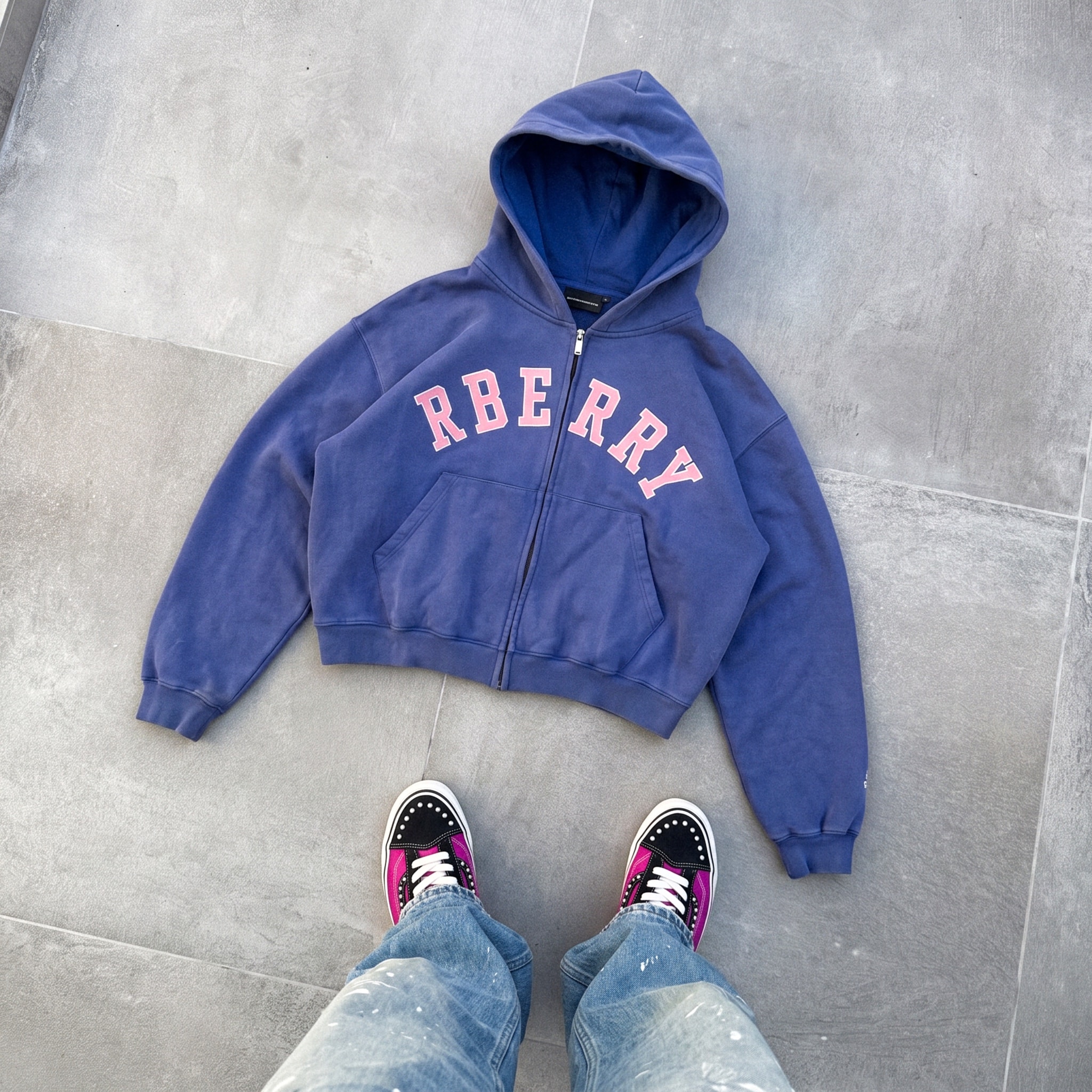 Blue zip hoodie laid flat above a pair of sneakers