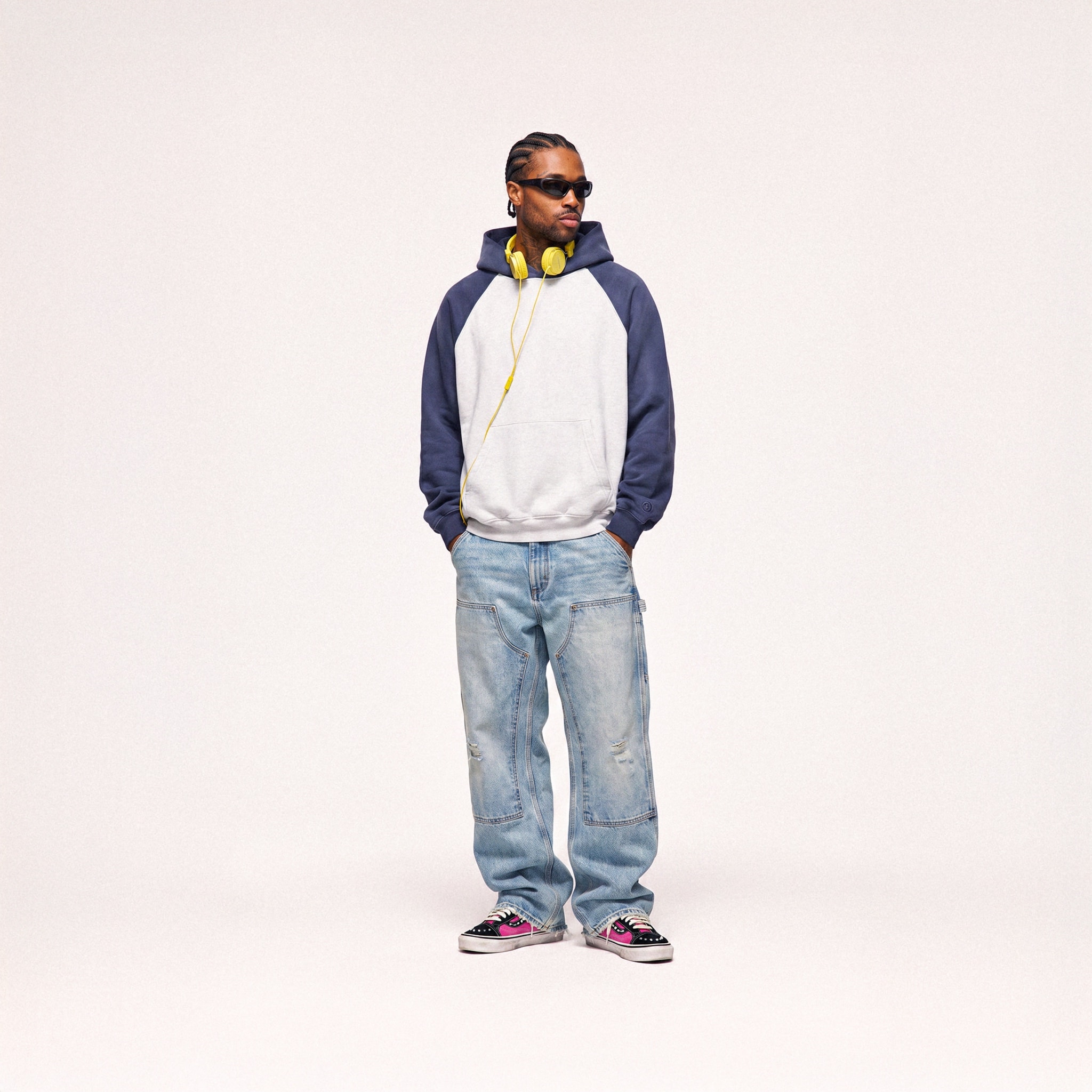 Model in a raglan hoodie and wide jeans on a pale backdrop